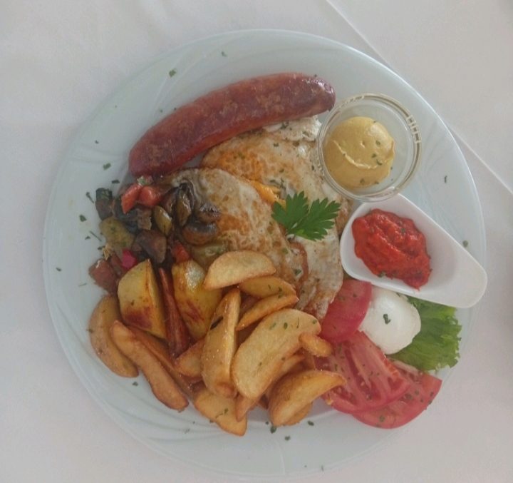 Traditional Bosnian breakfast plate — fried egg, kobasica sausage, roasted potatoes, ajvar and mustard, Banja Luka