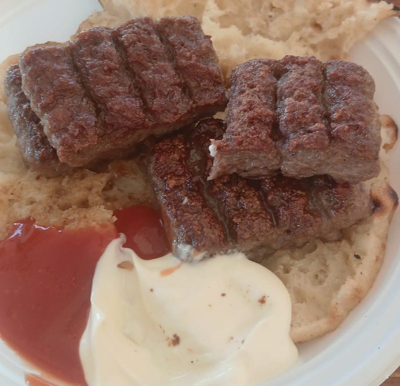 Bosnian ćevapi on somun flatbread with kajmak and ajvar — traditional grilled minced meat, Banja Luka