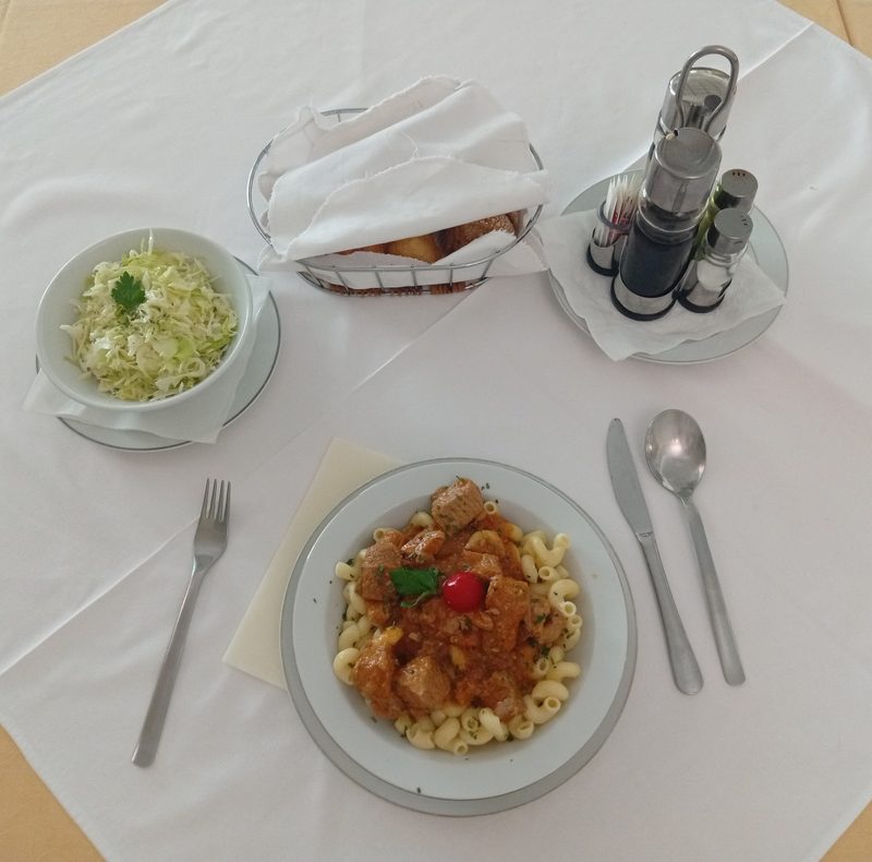 Bosnian restaurant table setting — goulash with macaroni, kupus salata, bread basket, a typical lunch in Banja Luka