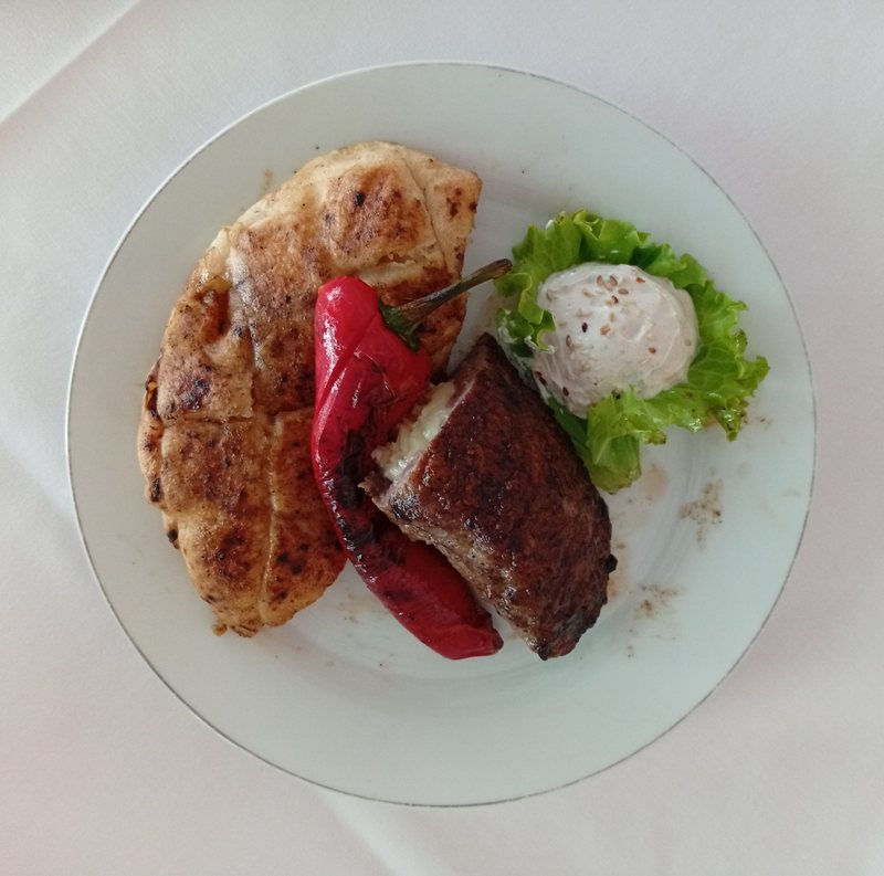 Cheese-stuffed pljeskavica with somun flatbread, grilled red pepper, lettuce and kajmak — Bosnian grill, Banja Luka