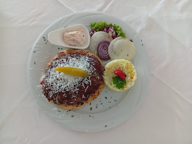 Pljeskavica topped with grated cheese on lepinja, with rice, onion, salad and kajmak — Bosnian grill, Banja Luka